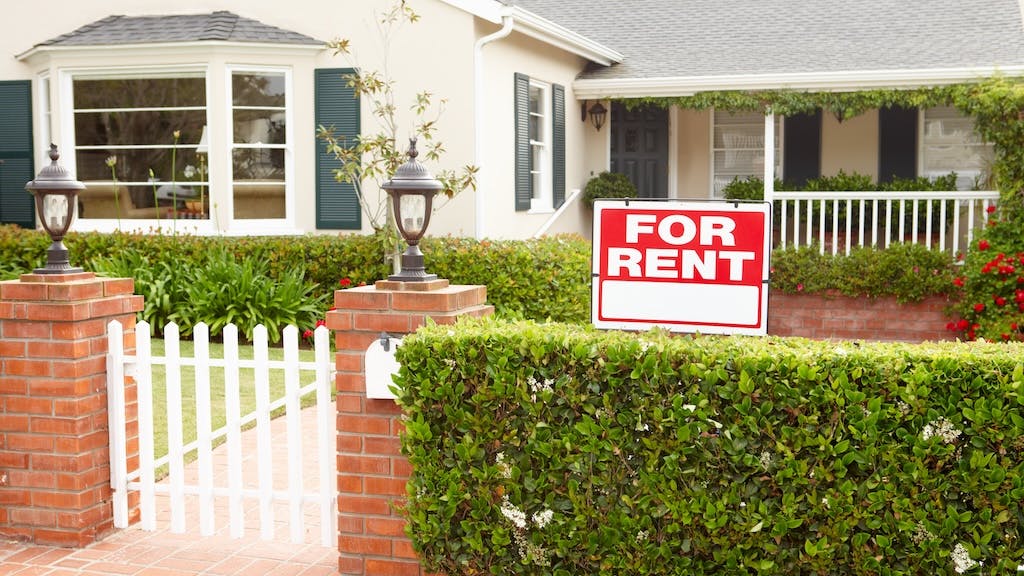 'For Rent' sign in front of a single-family home