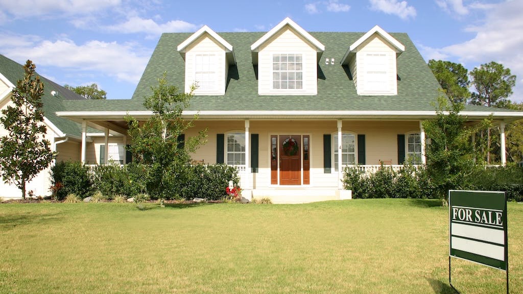 House with a 'For Sale' sign in the front yard