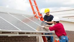 Workers install solar panels onto the roof of a home Workers install solar panels onto the roof of a home