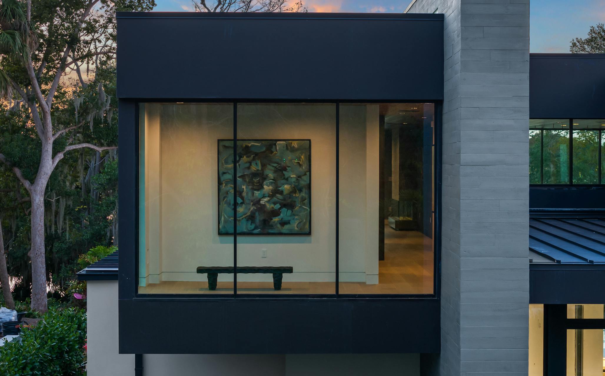 While most viewing areas orient to the lake, a private seating area within the primary suite footprint faces the front, offering a quiet space for the homeowner to enjoy privacy and select pieces of art.