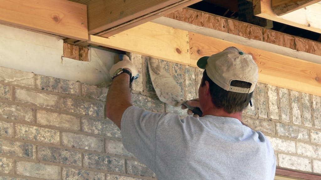 Mason laying brick on exterior of home
