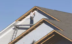 Worker hangs vinyl siding. Worker hangs vinyl siding.
