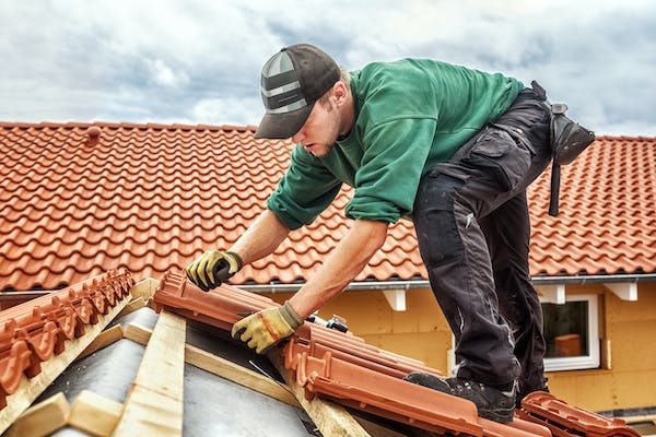 contractor working on a roof for a roofing job with brick