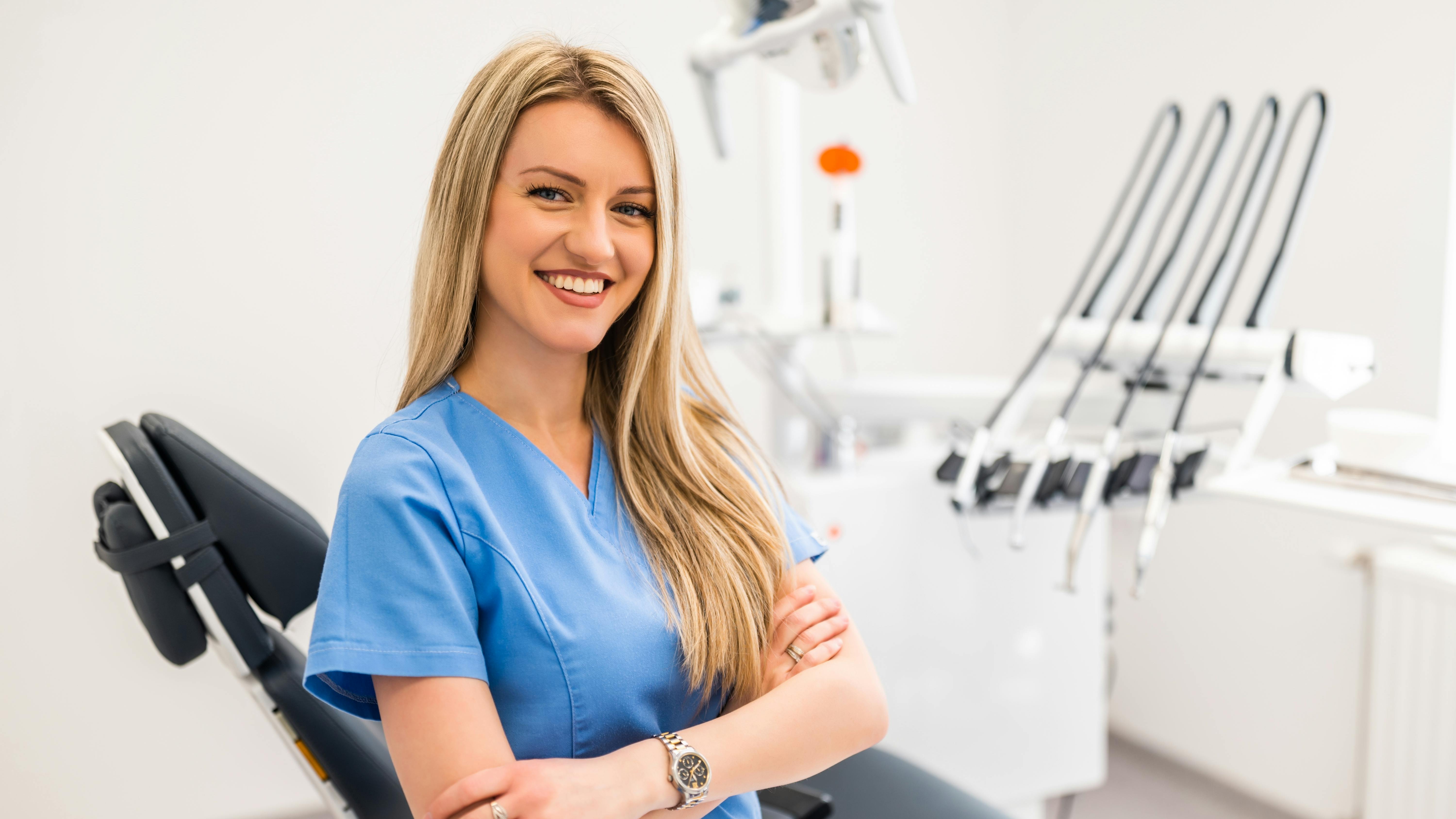 Smiling female dental hygienist in dental operatory