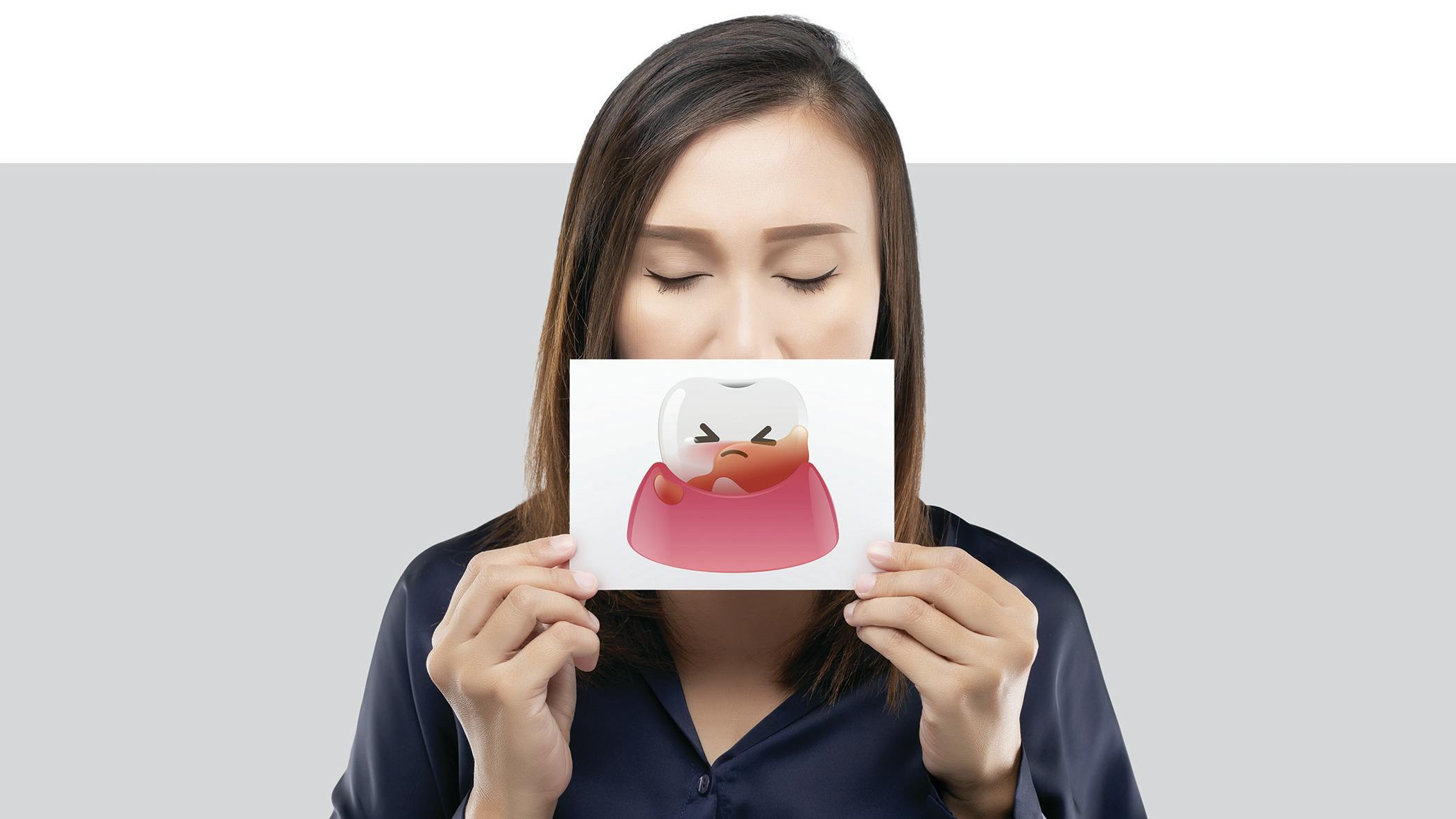 woman holding a picture of a tooth with a face on it
