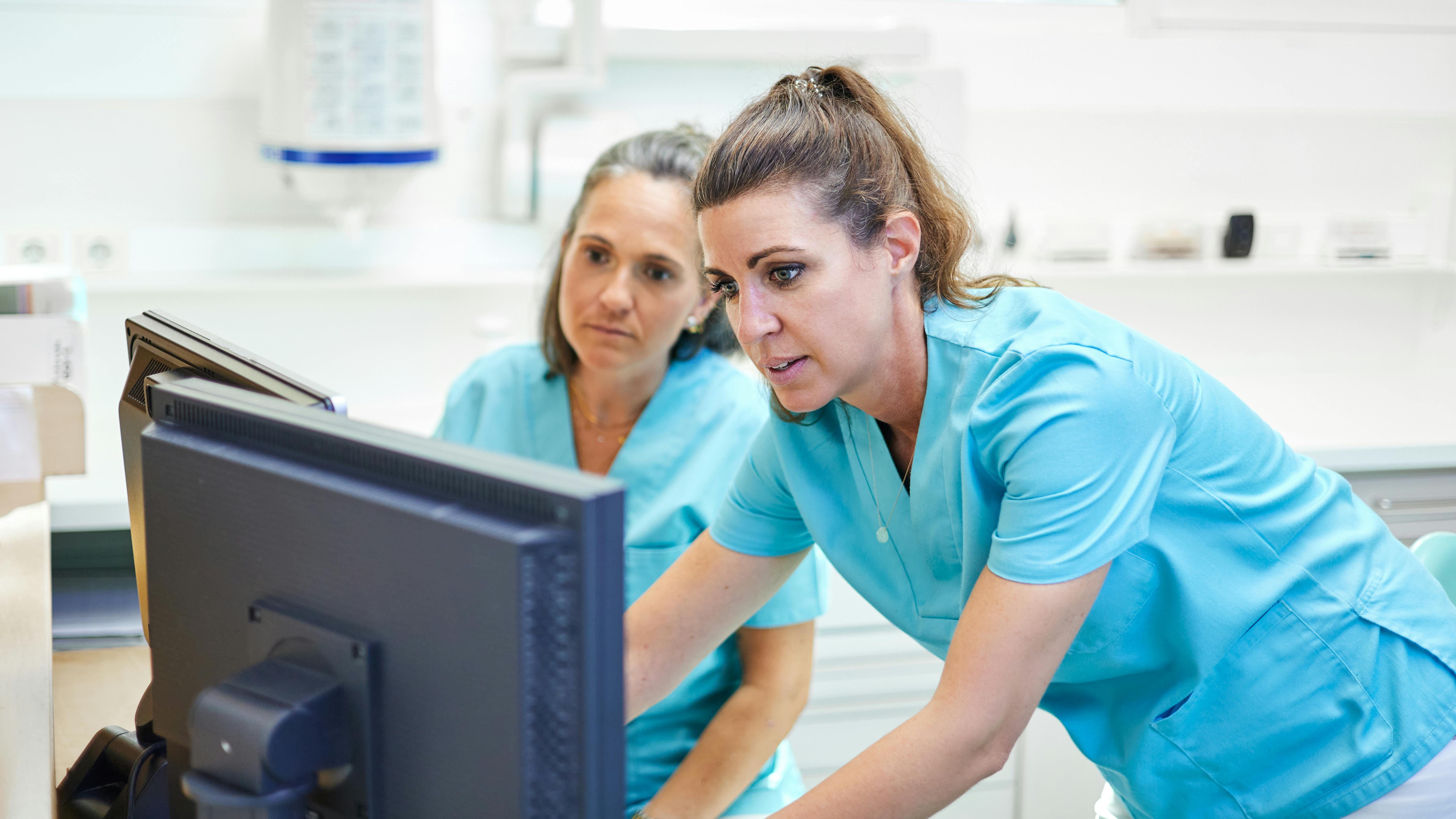 Dental hygienist and assistant reviewing patient care in operatory, illustrating oral preventive assistant role in practice