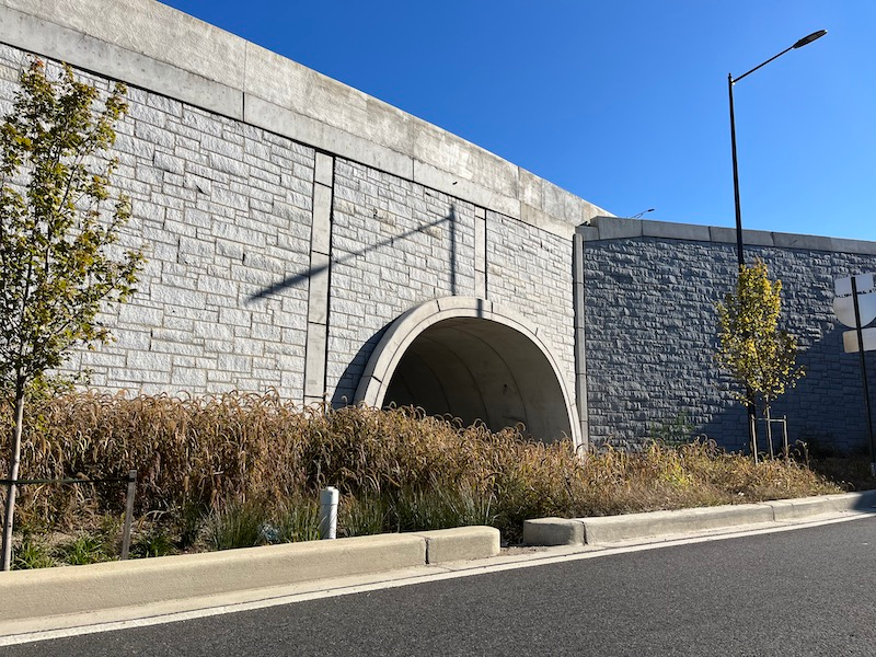 The completed TechSpan tunnel and a Reinforced Earth MSE wall with the final stone veneer.