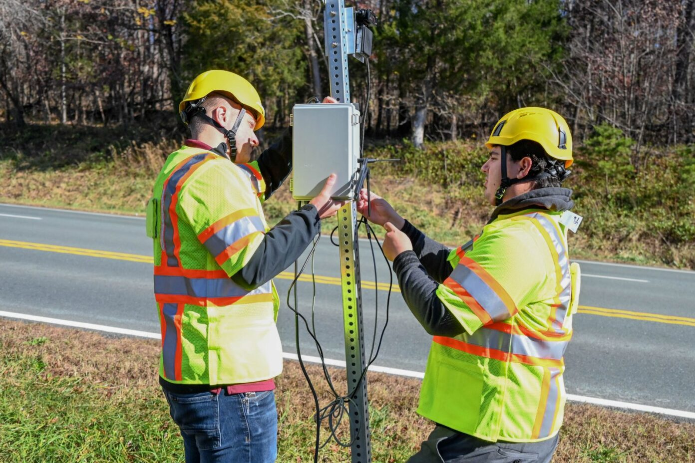 Virginia Tech Transportation Institute researchers (from left) Will Vaughn and Daniel Burdisso install part of the VTTI Smart Work Zone on a road sign. Photo by Jean Paul Talledo Vilela for Virginia Tech.