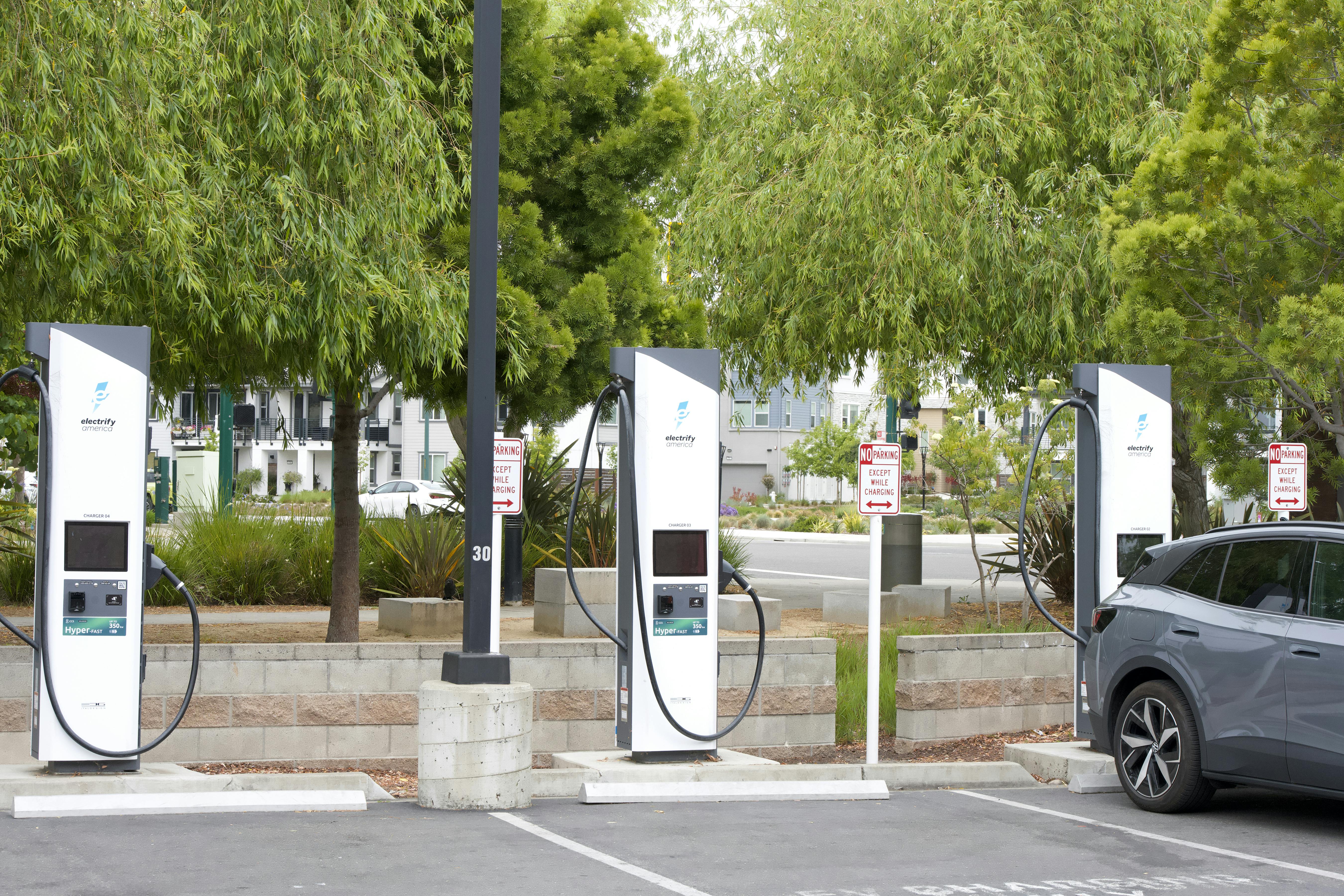 Three electric vehicle chargers and an electric vehicle being charged in a parking lot in California.