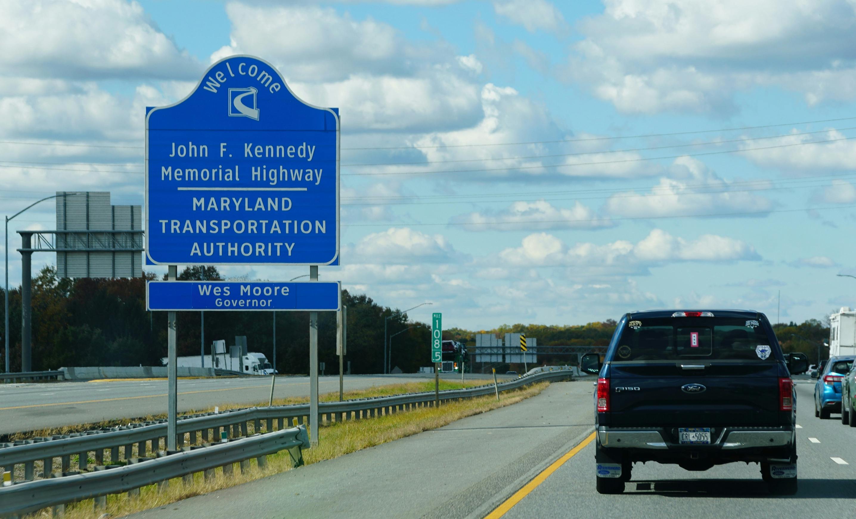 A sign on the side of a highway in Maryland welcoming drivers to the John F. Kennedy Memorial Highway.