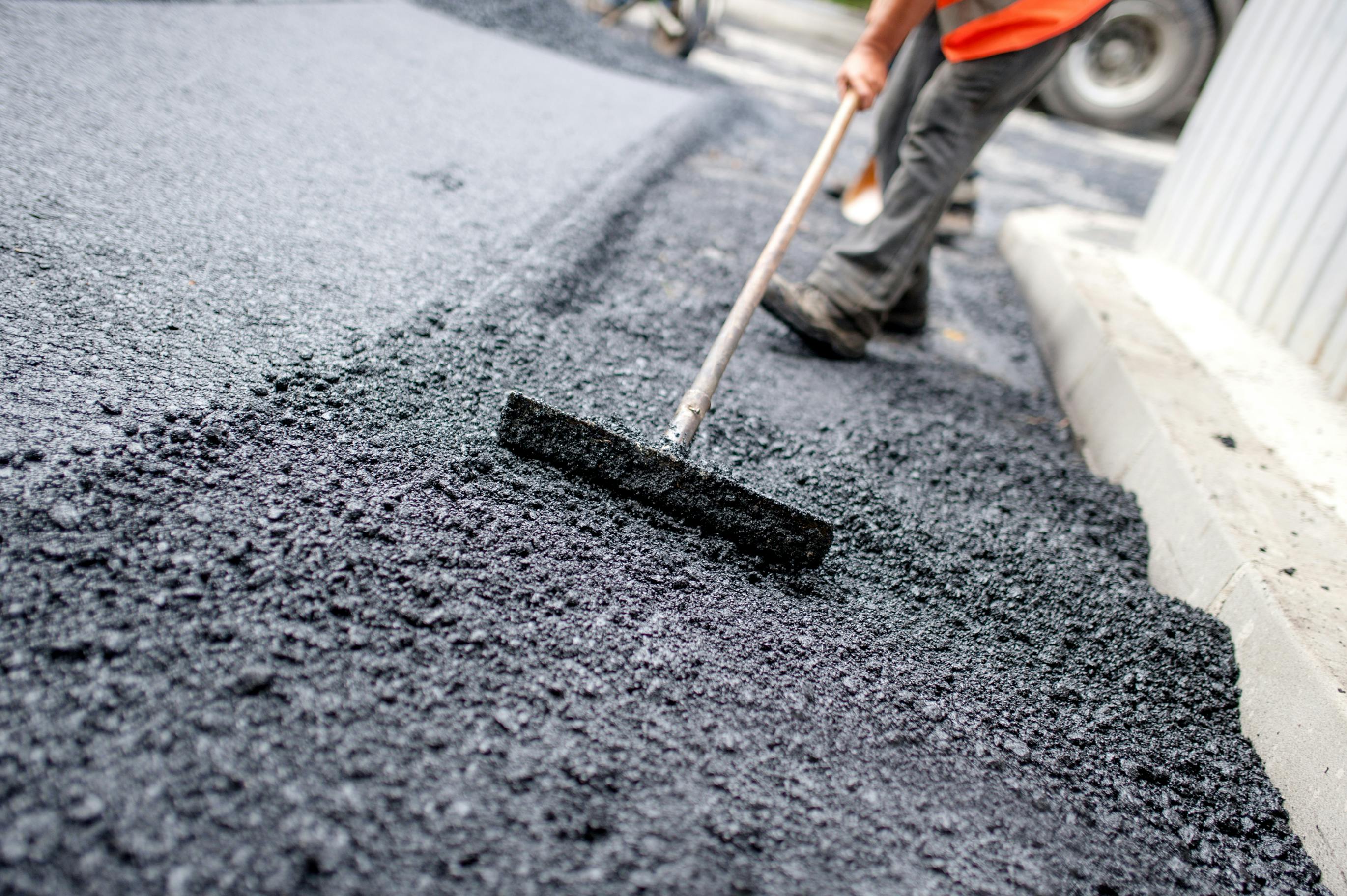 A person laying asphalt on a roadway.