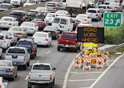 Bumper to bumper traffic on a highway with a sign informing drivers of an upcoming work zone ahead. Bumper to bumper traffic on a highway with a sign informing drivers of an upcoming work zone ahead.
