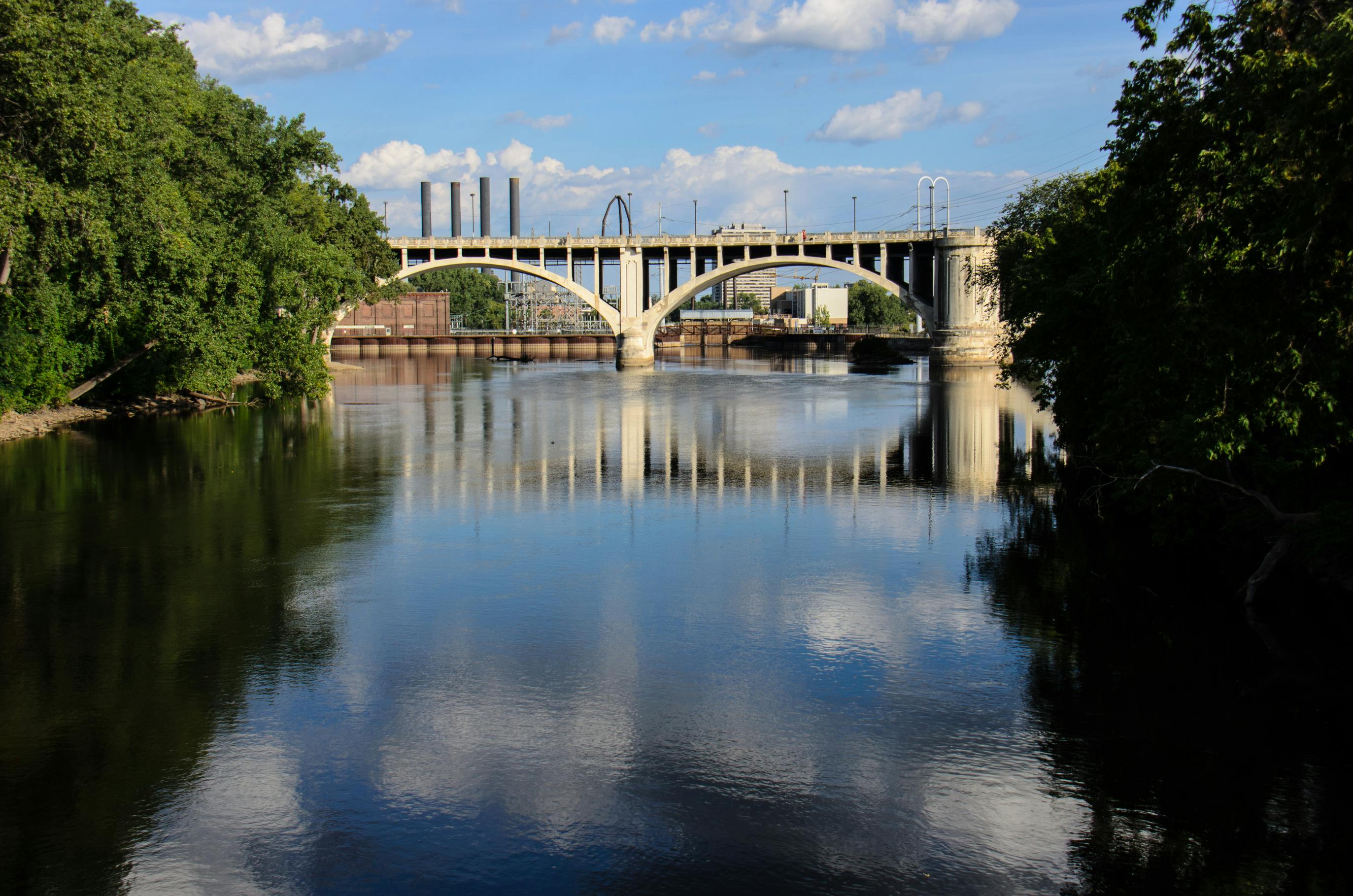 The I-35W Bridge rises over downtown Minneapolis, spanning the Mississippi River in the foreground
