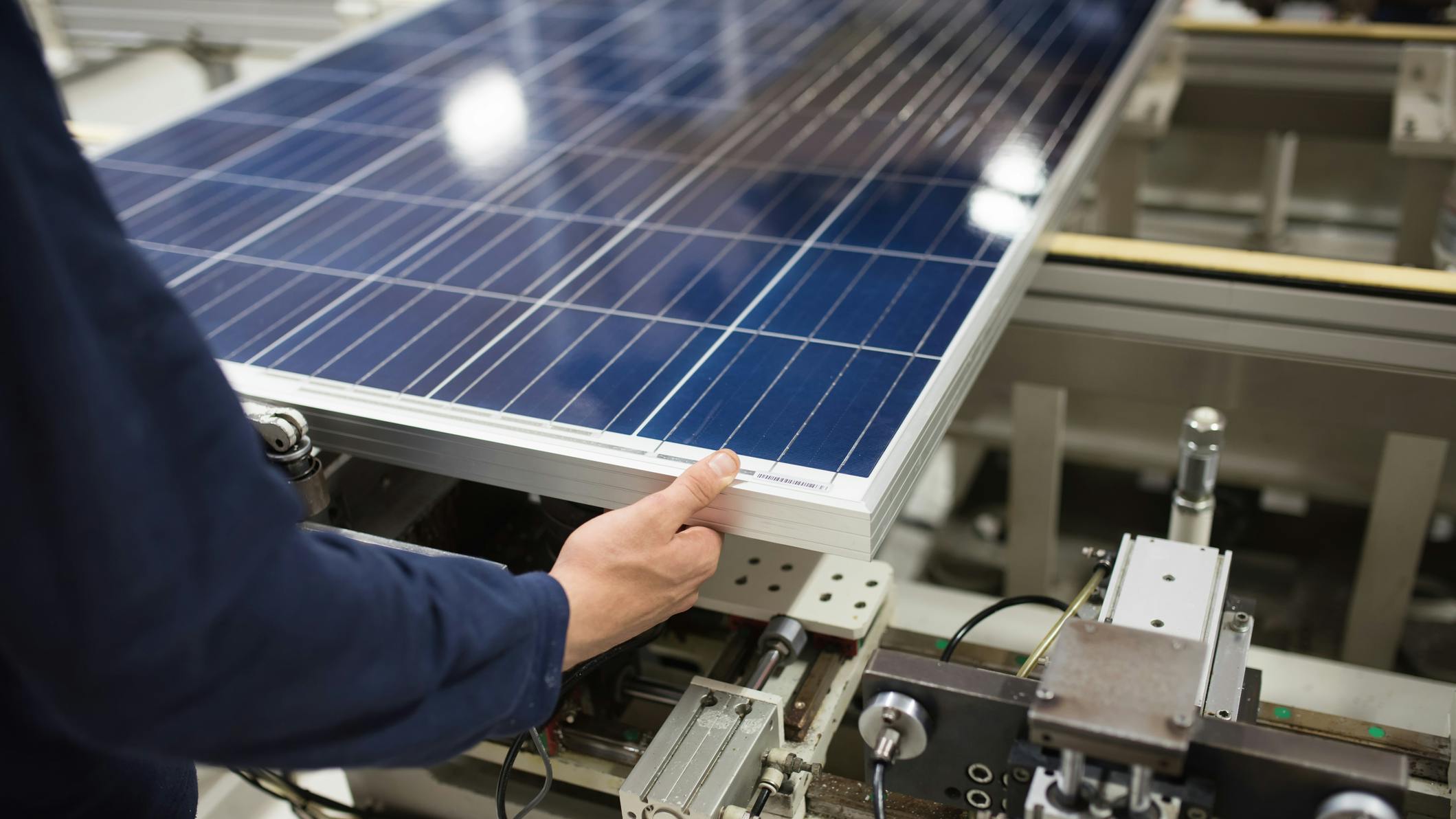 A production line worker helps assemble solar panels.