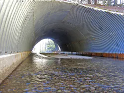 A large corrugated steel culvert in an arch shape. A large corrugated steel culvert in an arch shape.