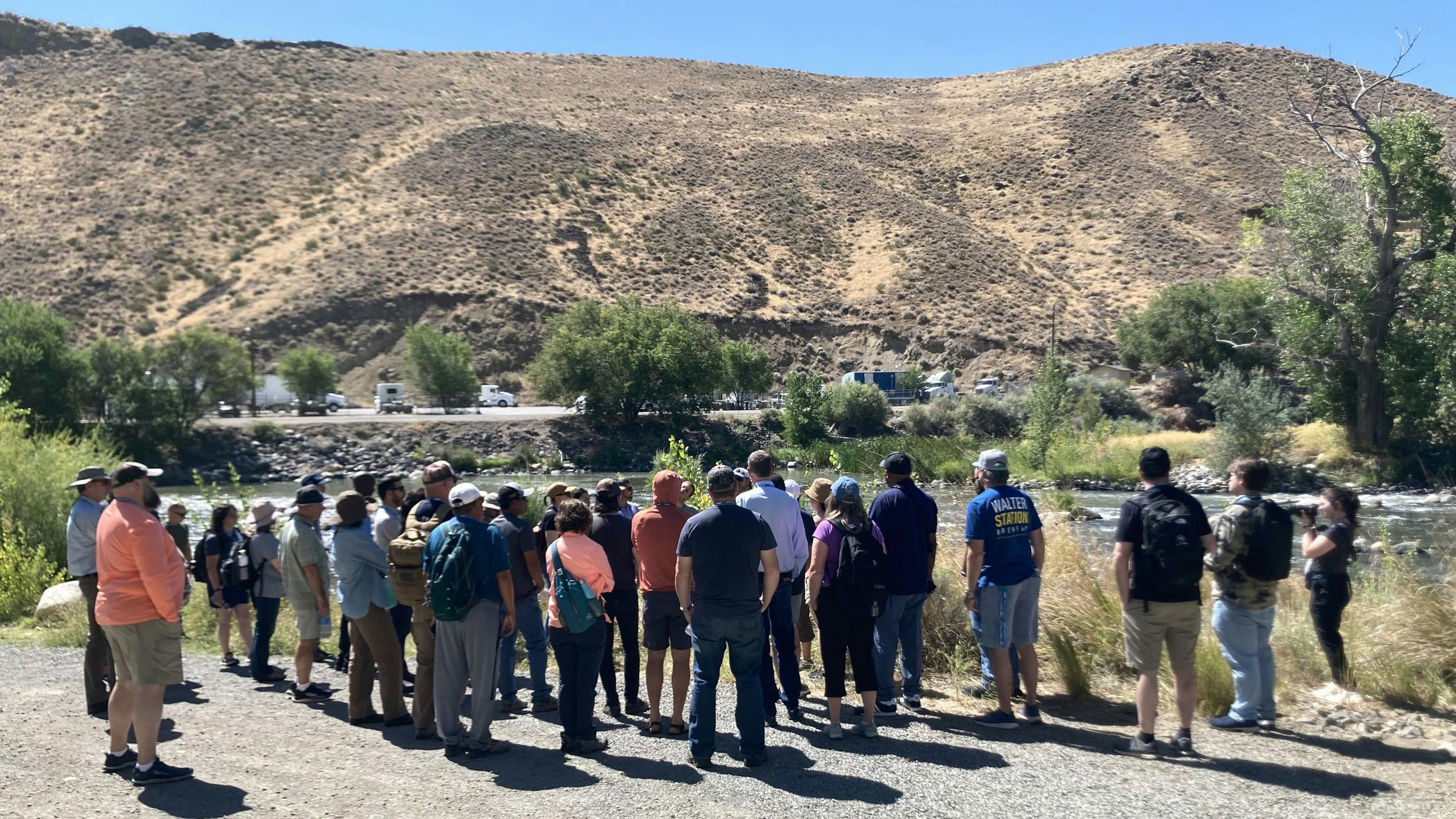 A group gathers around Danielle Henderson as she talks about Truckee River.