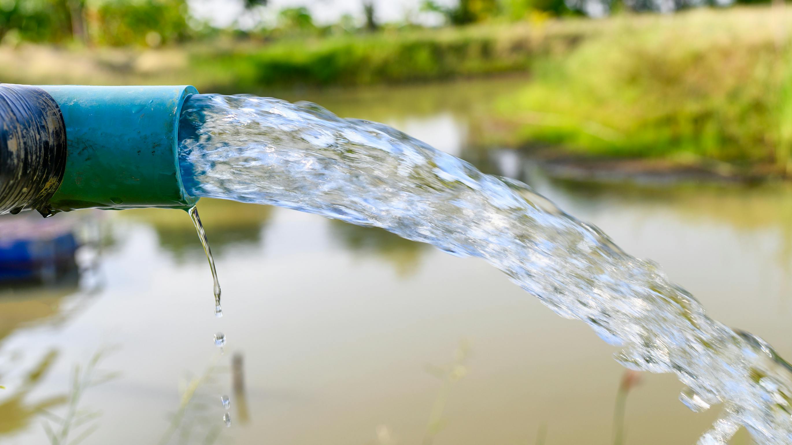 Agriculture blue pipe with groundwater gushing in pond