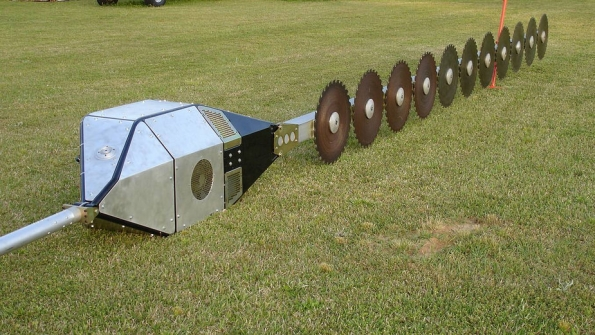 A closeup of the aerial saw on the ground with rotary blades and box housing the motor