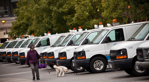 A woman walks with her dog past Con Edison trucks lined up in Union Square in preparation for Hurricane Sandy