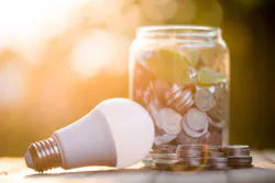 An energy-saving LED bulb next to a jar full of coins An energy-saving LED bulb next to a jar full of coins