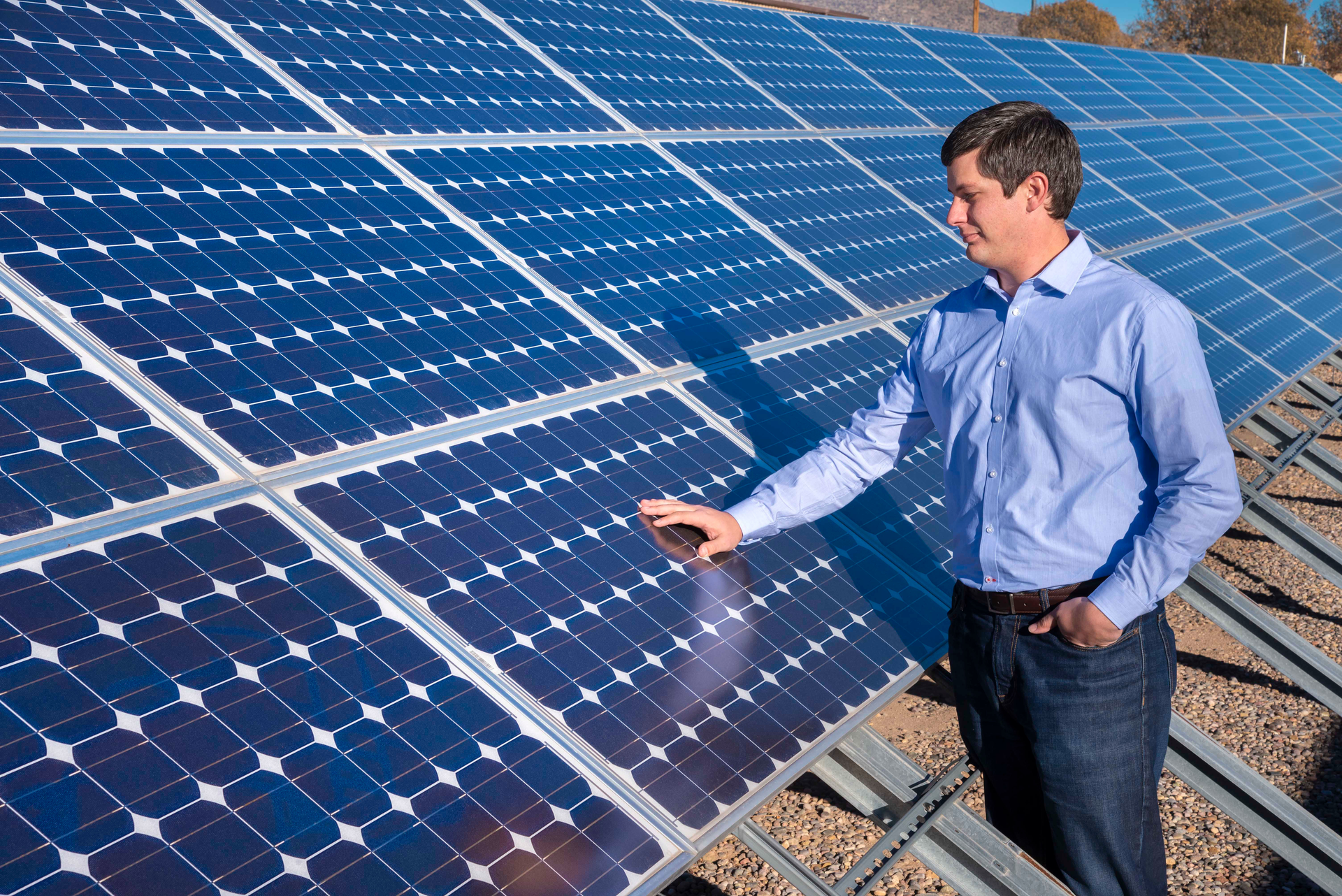 Matthew Reno with his hand on an array of solar panels