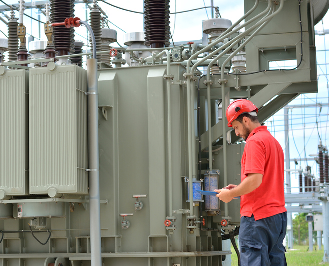 A worker studies looks at some documents near a transformer