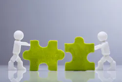 Two figures pushing two fitting jigsaw pieces Two figures pushing two fitting jigsaw pieces