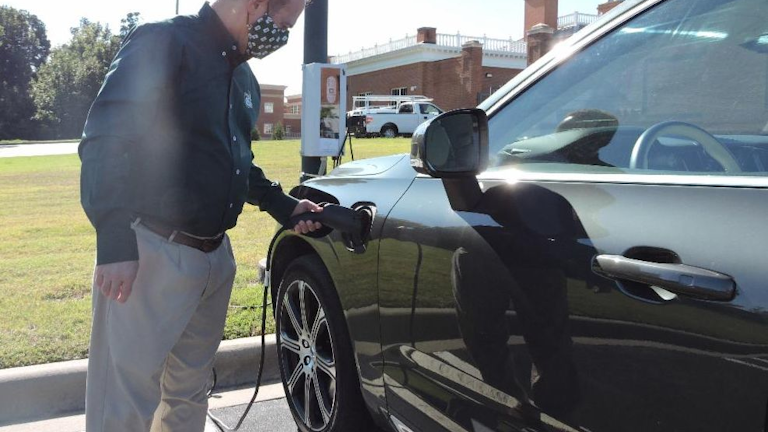 Figure 3. Dr. Rob Keynton, dean of the William States Lee College of Engineering, connects his plug-in hybrid electric vehicle to a Pole Volt charger (background) as part of early testing before a year-long public trial in Charlotte, North Carolina.