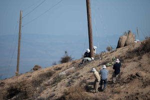SRP crews plumb a pole with rope after a helicopter set. The two employees next to the pole are adjusting the wedges.