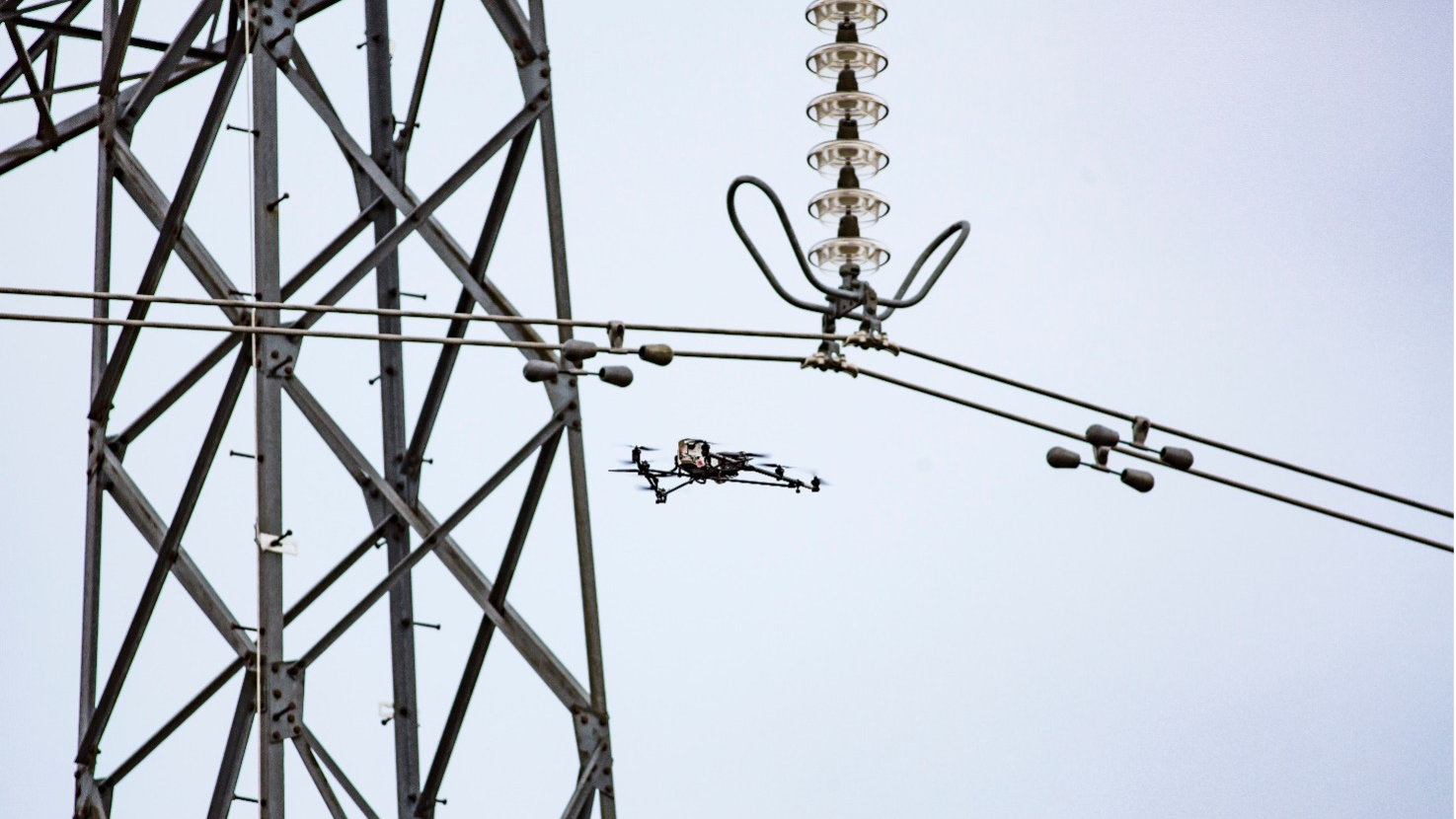 Drone conducts aerial inspection of transmission tower.