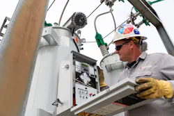 A substation technician inspects a voltage regulator control. A substation technician inspects a voltage regulator control.