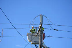 Linesman connecting a covered conductor to a bare conductor interface pole top structure. Linesman connecting a covered conductor to a bare conductor interface pole top structure.