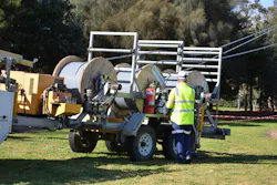 Trailer with drums of covered conductor being unwound during the conductor stringing of the overhead line. Trailer with drums of covered conductor being unwound during the conductor stringing of the overhead line.