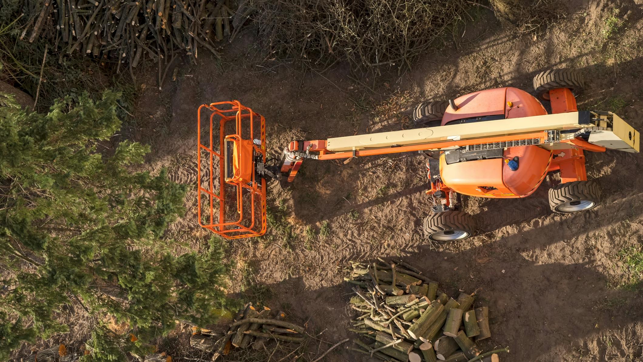 Aerial shot of an articulated boom lift positioned for tree trimming.