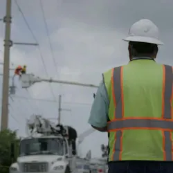 A job site manager oversees a lineman working from his bucket. A job site manager oversees a lineman working from his bucket.