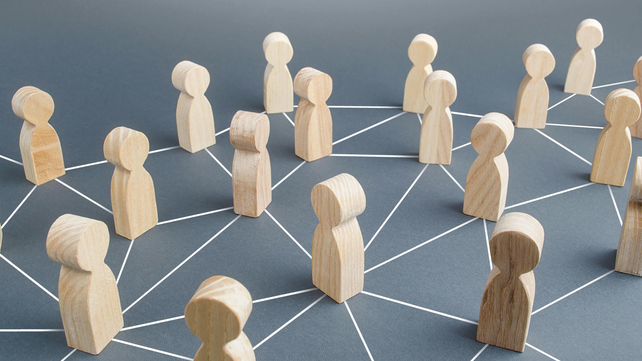 Wooden people connected by lines representing collaboration and cooperation.
