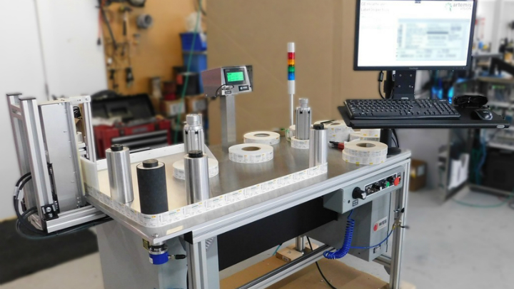 Figure 1: To inspect medical imaging product labels, an operator opens a label recipe on an HMI, loads a label roll onto the table, and strings it through rollers in front of a CIS line scan camera.