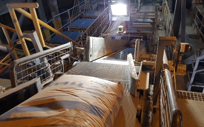 Figure 1: Three cameras are mounted above the production line to inspect the cement sacks. Two color cameras scan for defects such as splits, holes, cracks, and spills. A third monochrome camera (above) scans for printing errors. A DC LED light is also placed above the line to overcome ambient light issues.