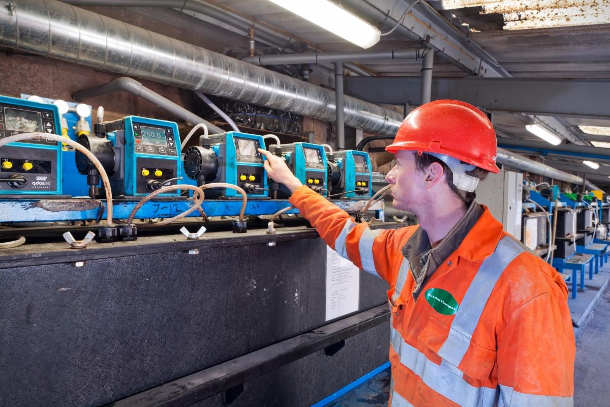 A worker inspects a Qdos peristaltic chemical metering pump.