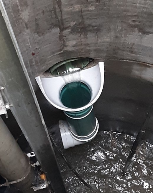 A fiberglass drop bowl is bolted to the manhole wall just beneath the high-level inflow pipe.