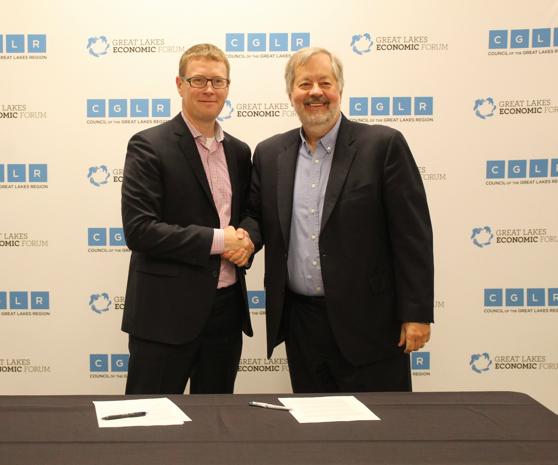Mark Fisher, president and CEO of the Council of the Great Lakes Region, and Dean Amhaus, president and CEO of The Water Council shake hands after signing partnership agreement.
